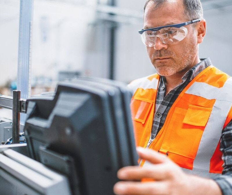 Male industrial worker working with manufacturing equipment in a factory