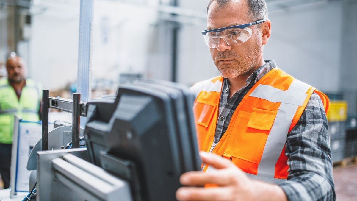 Male industrial worker working with manufacturing equipment in a factory