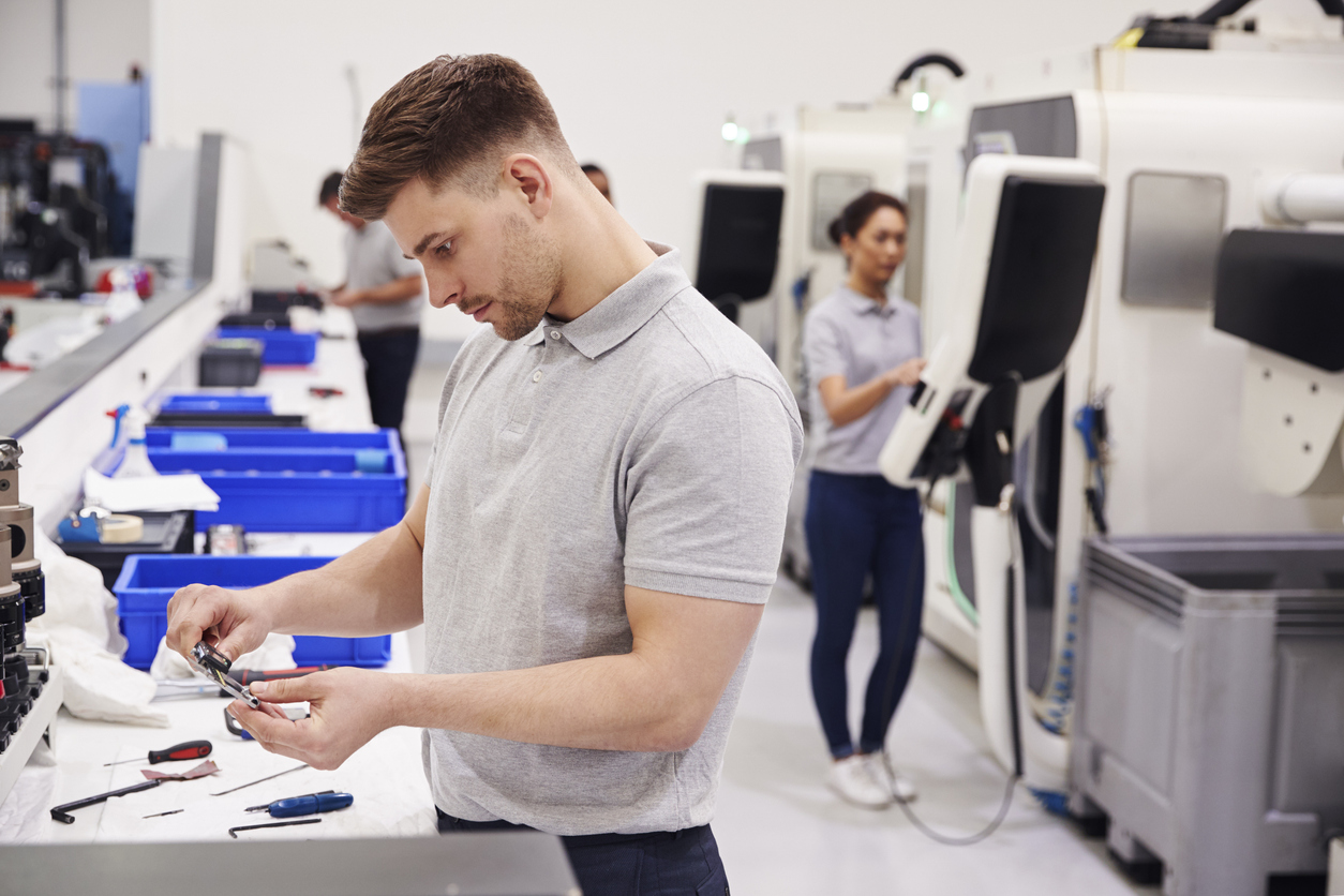 Picture illustrating Manual Testing in Electronics Manufacturing. Picture of Male Engineer Quality Controlling Components In Factory.