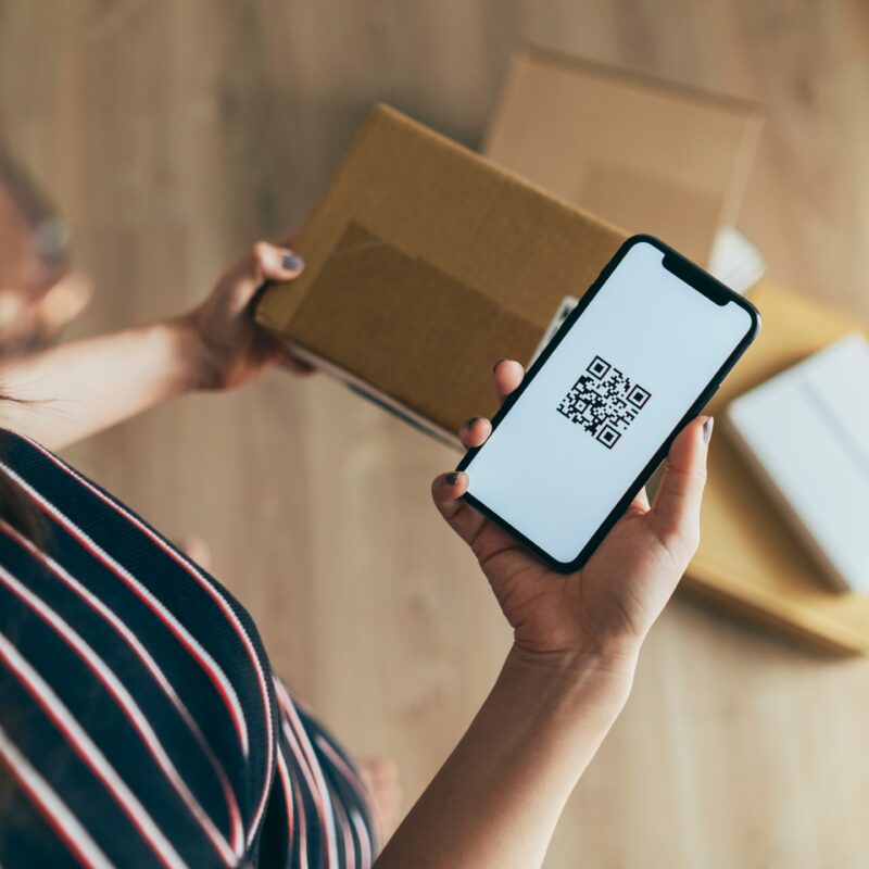 Photo to illustrate RMA, return merchandise authorization. Woman with a package and a QR code.